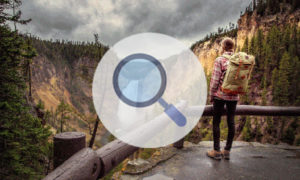 Magnifying glass centered between man looking into national forest.