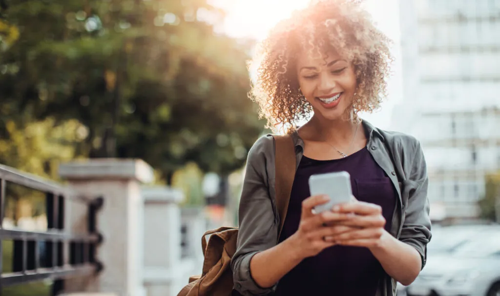 female on a sunny day in a retail area on her mobile device