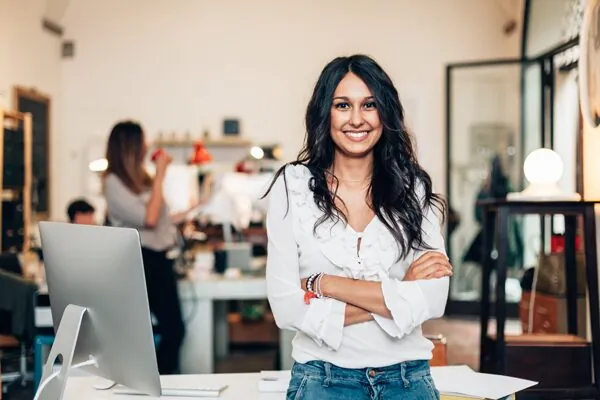 woman with black wavy hair in a white shirt with arms crossed